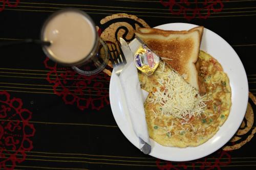 a plate of omelet with a fork and a glass of milk at Sayang Mama Inn in Gili Air
