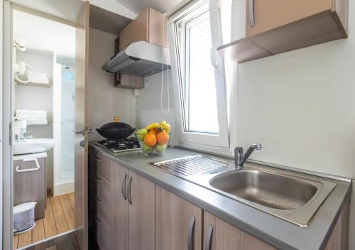 a kitchen with a sink and a bowl of fruit on the counter at Krk Mobile Homes in Klimno