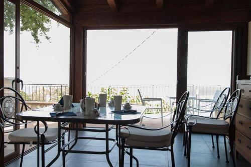 ein Esszimmer mit einem Tisch, Stühlen und Fenstern in der Unterkunft B&B Le Rose del Tirreno in Falerna