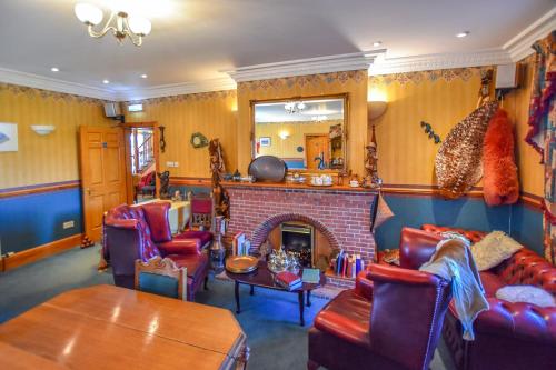 a living room with a fireplace and red chairs at Herrislea House Hotel in Tingwall