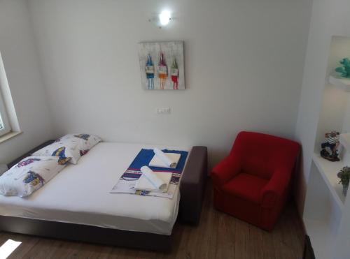 a bedroom with a bed and a red chair at Apartment Luka in Makarska