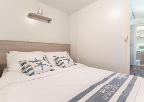 Un dormitorio con una cama blanca con almohadas azules y blancas en Krk Mobile Homes en Klimno