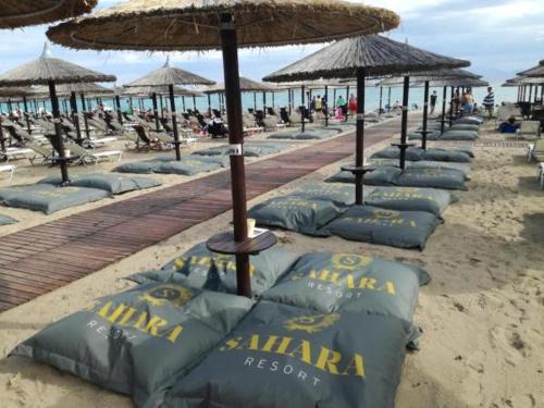 a row of beach chairs and umbrellas on a beach at Crystal Blue Apartments in Nea Kalikratia