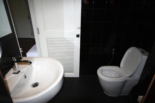 a bathroom with a white toilet and a sink at Hotel Alley in Hua Hin