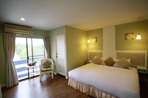 a bedroom with a large white bed and a window at Hotel Alley in Hua Hin