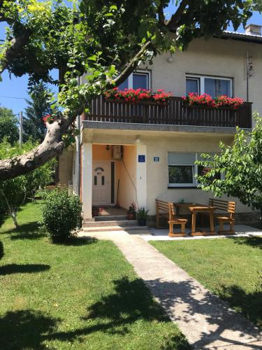 una casa con tavolo e balcone con fiori rossi di Guest House Josipović a Korenica