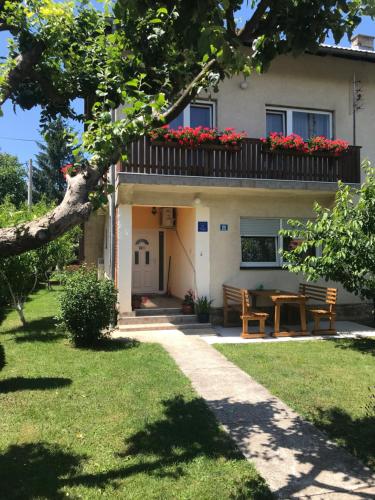 a house with a table and a balcony with red flowers at Guest House Josipović in Korenica