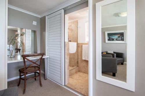 a room with a shower with a chair and a table at Cliff Lodge in Gansbaai