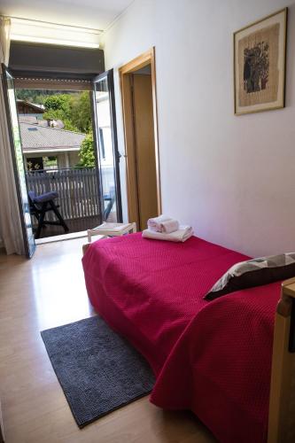 a bedroom with a red bed and a balcony at Hotel Park Oasi in Arta Terme