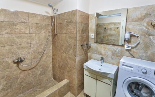 a bathroom with a shower and a sink and a washing machine at Apartments Harmonia Colours in Budva
