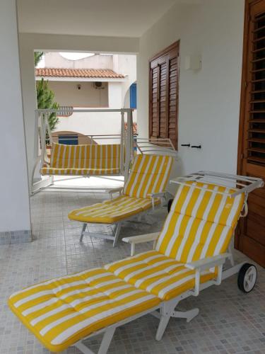 two yellow and white chairs sitting on a porch at VILLA VEGA in Fontane Bianche