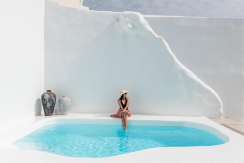 a woman sitting in a hot tub in a white room at Aspaki by Art Maisons in Oia