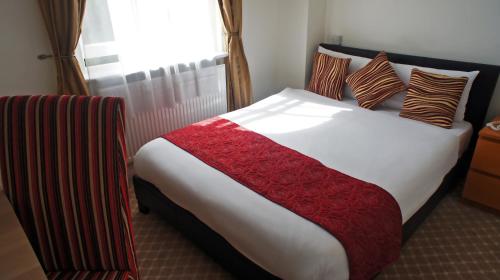 a bedroom with a large bed with a red blanket at Abbey Court Hotel - Hyde Park in London