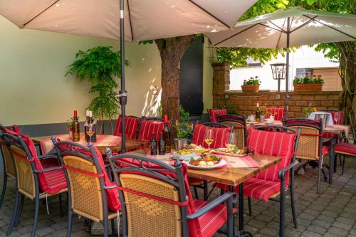 un restaurante con sillas rojas, mesas y sombrillas en Goldener Pfropfenzieher, en Oberwesel