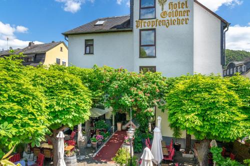 a building with trees and umbrellas in front of it at Goldener Pfropfenzieher in Oberwesel
