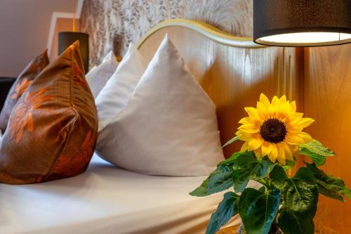 a vase with a sunflower on a bed with pillows at Goldener Pfropfenzieher in Oberwesel