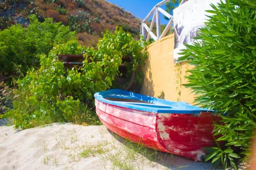 a red and blue boat sitting on the sand at Hotel Grotticelle in Capo Vaticano