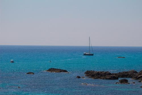 a sailboat in the ocean with rocks in the water at Hotel Grotticelle in Capo Vaticano