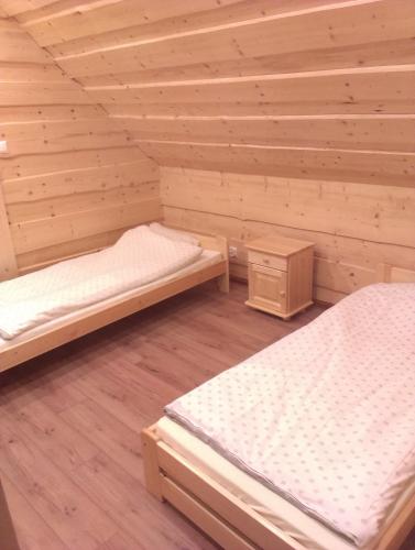 a room with two beds in a wooden room at Słoneczne Chaty pod Sonami Kasina Wielka in Kasina Wielka