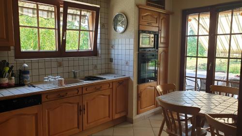 - une cuisine avec des placards en bois, une table, une table et des chaises dans l'établissement location à la campagne aux portes de Mulhouse, à Sausheim