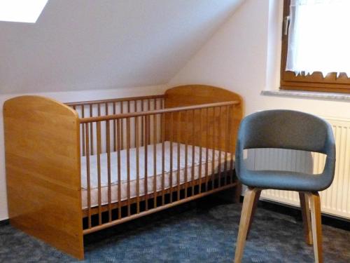 a crib and a chair in a room at Auf der Heide in Borkheide