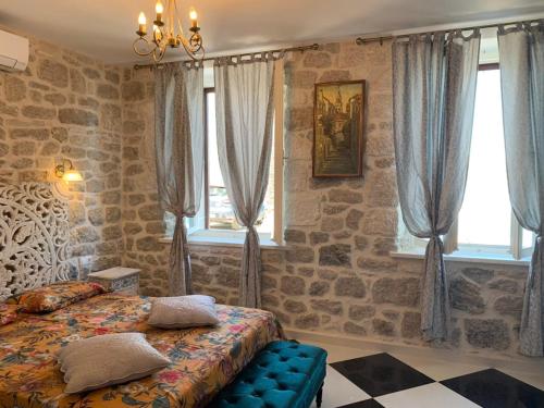 - une chambre avec des murs en pierre, un lit et des fenêtres dans l'établissement Apartment Romano, à Korčula