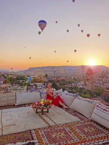 a woman sitting on a rooftop watching hot air balloons at Henna Hotel-Adults Only in Goreme