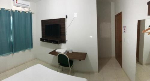 Zimmer mit einem Schreibtisch und einem TV an der Wand in der Unterkunft BRAVO CITY HOTEL CAMPO VERDE in Campo Verde