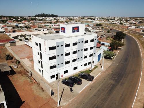 ein weißes Gebäude mit Autos, die vor einer Straße geparkt sind in der Unterkunft BRAVO CITY HOTEL CAMPO VERDE in Campo Verde