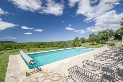 a swimming pool with chairs and a blue sky at Fleur de Lys in Fayence
