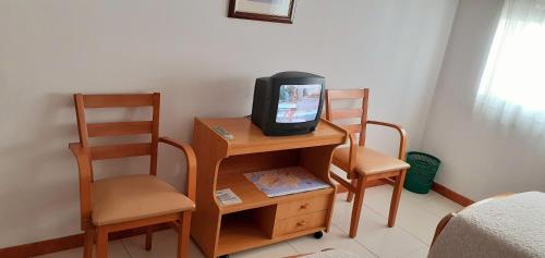 un televisor sentado en una mesa con dos sillas en Hostal El Cairo, en Ferrol