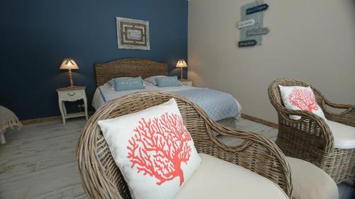 a bedroom with a bed and a wicker chair and pillow at DOMAINE DU BOIS SEGUIN in Saint-Loubert