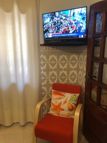 a chair with a pillow and a television on a wall at Starfish House in Vila Nova de Gaia