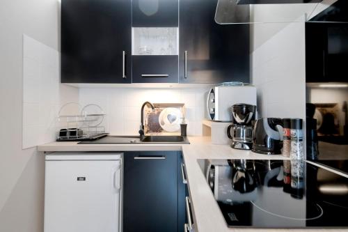 a kitchen with black and white cabinets and appliances at :) Grand studio lumineux à Toulouse et parking in Toulouse