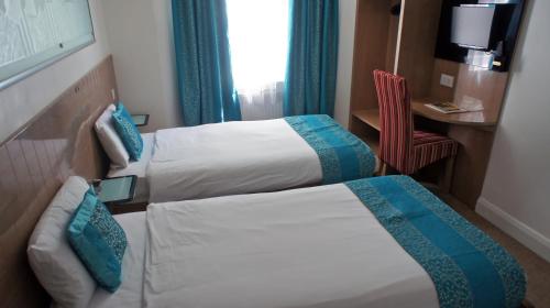 a hotel room with two beds and a chair at Abbey Court Hotel - Hyde Park in London