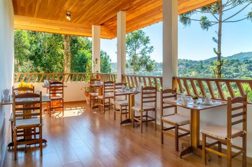 a dining room with tables and chairs and a balcony at Pousada Jardim da Mantiqueira in Monte Verde