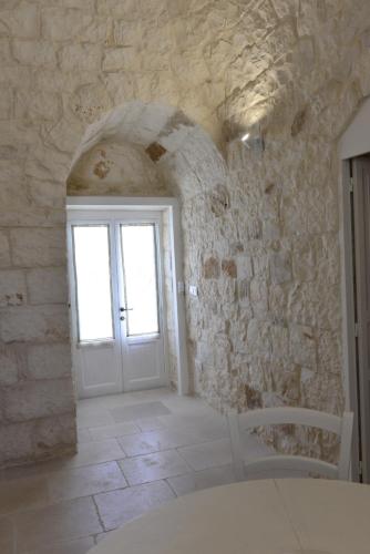 Cette chambre est dotée d'une porte blanche et d'un mur en pierre. dans l'établissement Masseria Gravinella, à Fasano
