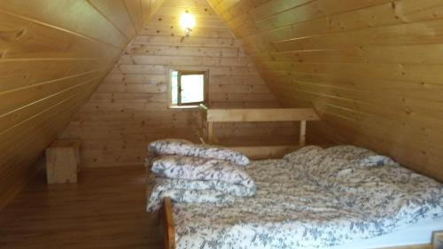 a bedroom with a bed in a wooden cabin at Chatka Nad Strumieniem in Glinka