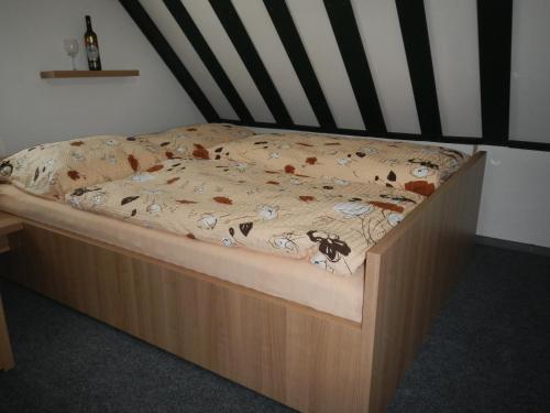 a bed with a wooden frame with a comforter on it at Cyklo ubytování a vinný sklep Žádovice in Žádovice