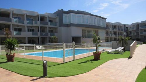 a large building with a swimming pool in front of it at Chocolate Brownie Piscina, Terraza, Planta baja, parking y WIFI in Corralejo