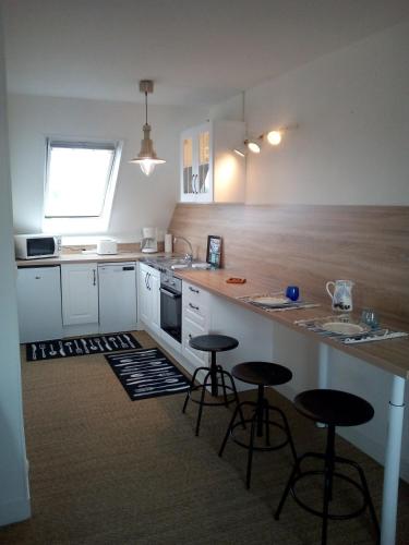 une cuisine avec deux tabourets de bar et un comptoir dans l'établissement Terrasses de Loire 1er étage, à Saint-Clément