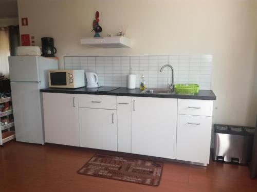 a kitchen with white cabinets and a sink and a refrigerator at Casa Lagoa Verde in Esmoriz