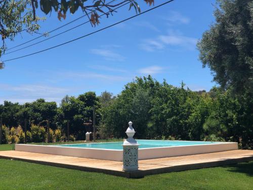 a swimming pool with a statue in the grass at Laranjal Farm House - Casa da Lareira in Faro