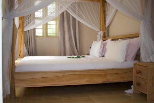 a bedroom with a canopy bed with white pillows at Paje Beach Apartments & Hotel in Paje
