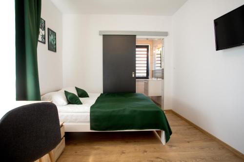 8 Jezior في أوغستوف: غرفة نوم مع سرير مع بطانية خضراء عليه