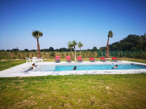 un grupo de personas nadando en una piscina con palmeras en Mas Puig, en Saint-Génis