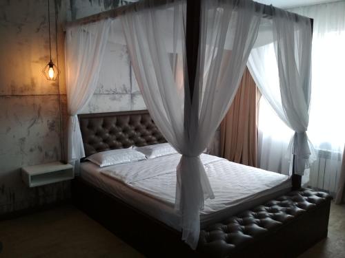 een slaapkamer met een hemelbed en witte gordijnen bij LOFT - Interior design apartments in Oral