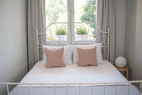 Cama blanca con almohadas rosas y ventana en TS City Centre Apartment en Szczecin