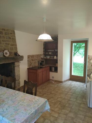 a living room with a table and a fireplace at Le Botcol in Plouguernével