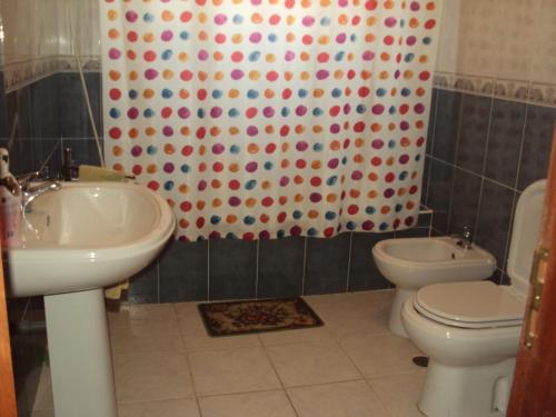 a bathroom with a sink and a toilet and a shower curtain at O Miradouro in Fonte Longa